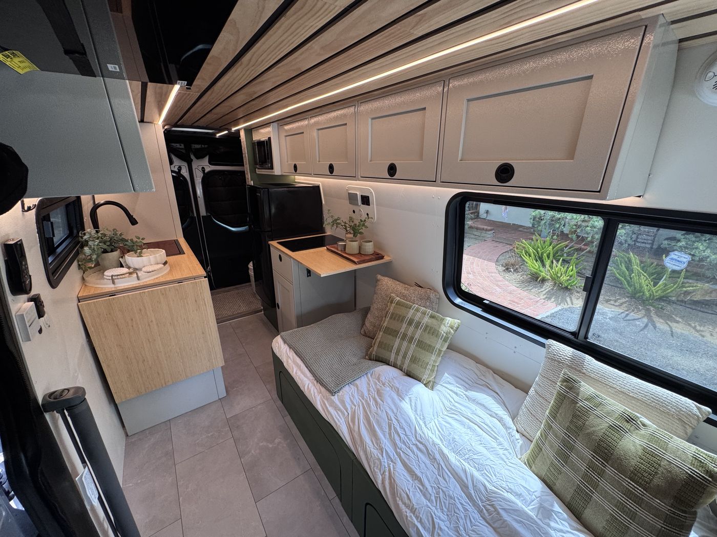 Grove Sprinter living area with bench bed, olive green accents and pine slat ceiling