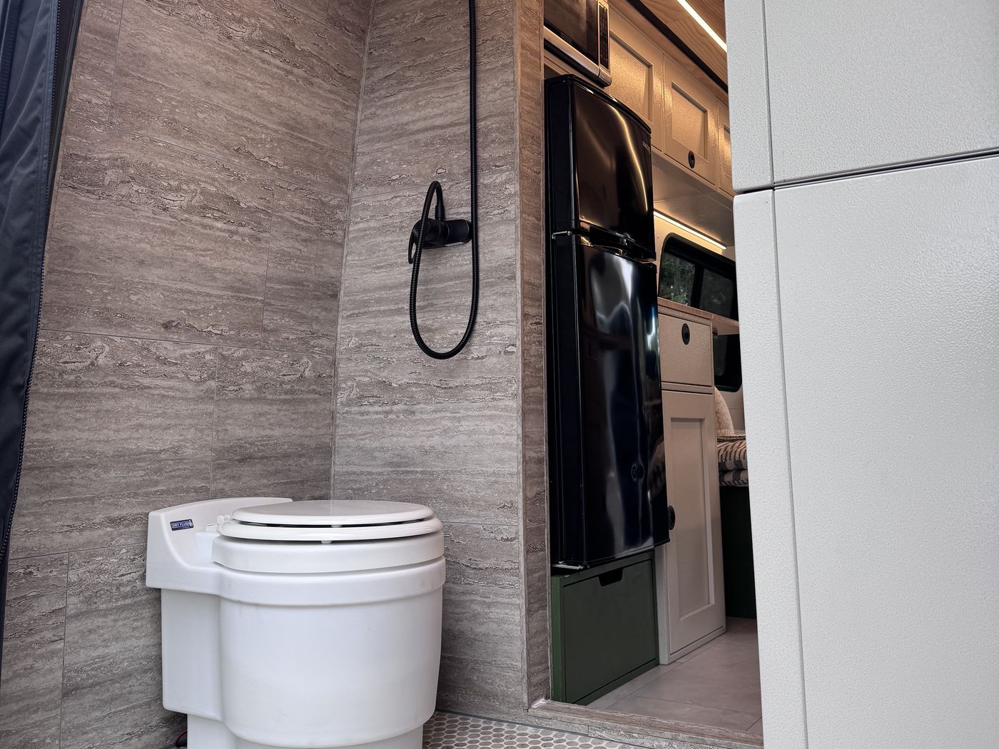 Grove Sprinter rear wet bath with travertine tile, penny round mosaic floor and dry flush toilet