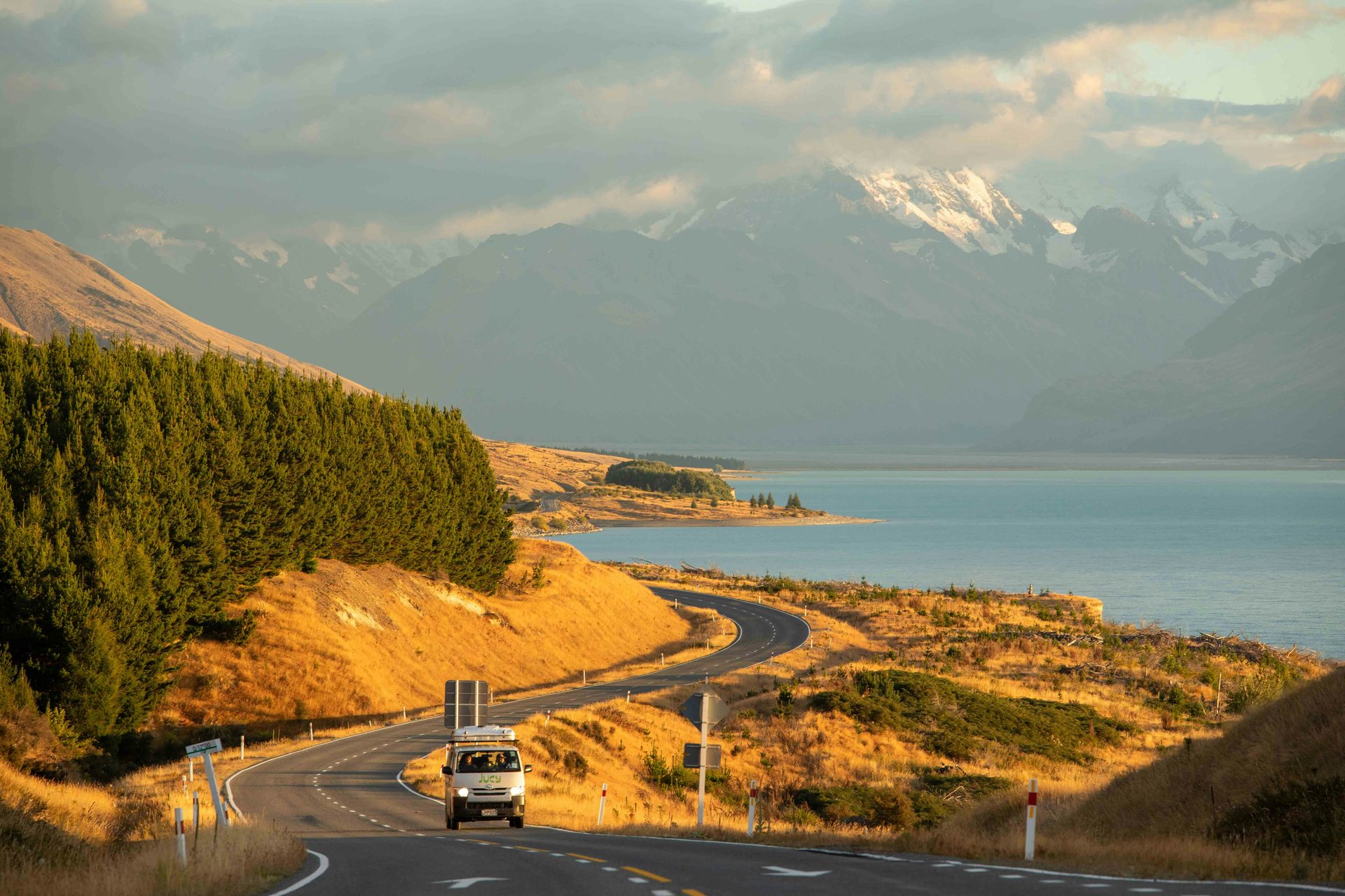 Camper van driving along a coastal highway — full-time van life on the road