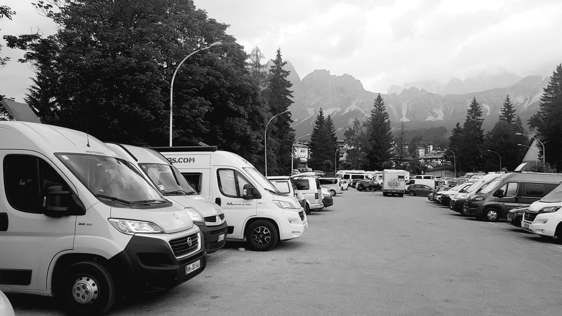 Multiple camper vans gathered at a mountain parking lot