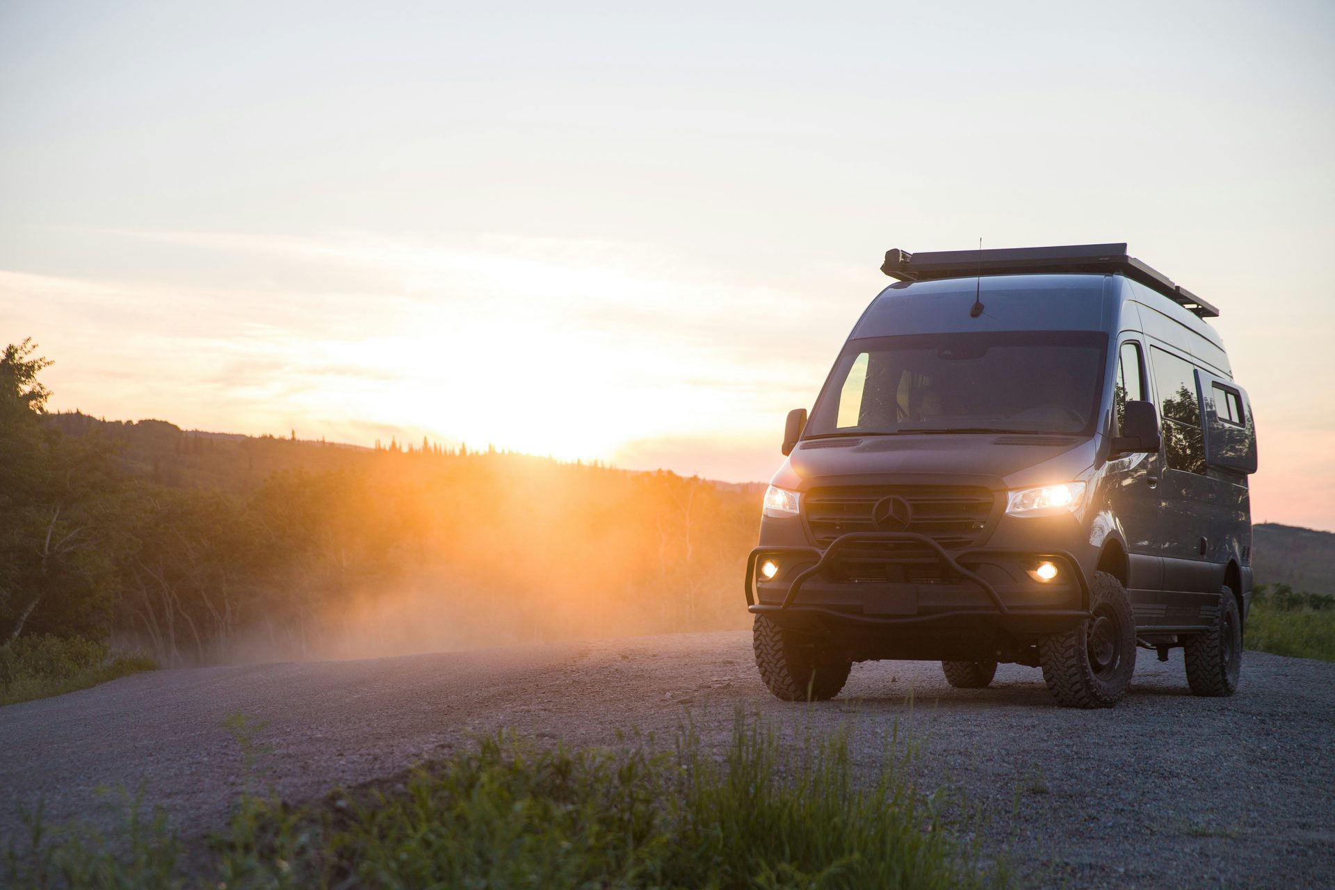 Mercedes Sprinter 4x4 van on a dirt road at sunset